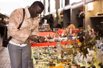 African American man chooses antiques on the flea market