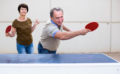 Mature man and woman playing table tennis