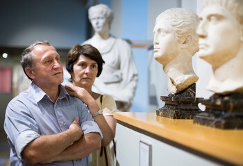 Mature couple turists examines the exhibit in museum