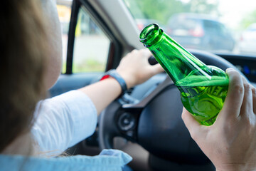 Someone driving and holding a bottle with alchohol. Drunk driving concept