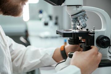 Professional laboratory worker is using microscope