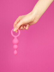 Woman's hand holding adult sex toy over pink background - 779789985