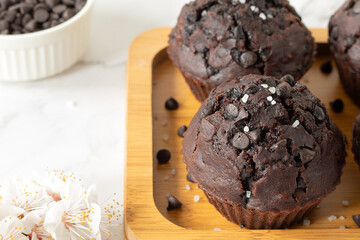Dark chocolate chip muffins with cocoa and bananas on wooden plate. Healthy sweet vegan dessert or snack. Close-up.