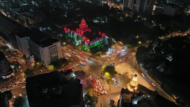 Aerial footage of traffic congestion at Church Gate station with colorful lighting of the Indian flag in the background and a view of the Mumbai skyline featuring high-rise buildings in South Mumbai