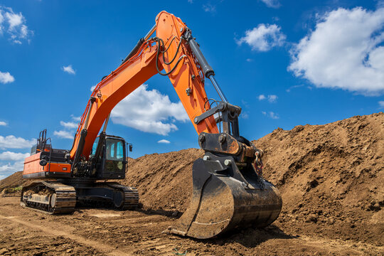 A large industrial excavator work on the construction site.  Cloudy sky