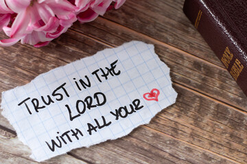 Trust in the LORD with all your heart, handwritten quote with holy bible book and flower on wood. Christian love, faith and hope in God Jesus Christ, biblical concept. - obrazy, fototapety, plakaty