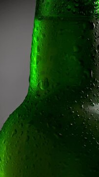 Classic green bottle of cold beer with condensate. Tilt shot with rotation. Vertical shot