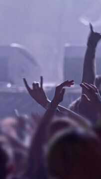 Fans at rock concert. People raising and claping their hands in stage lights. Unrecognizable fans dancing at a concert or festival party. Silhouettes of concert crowd , Vertical Screen