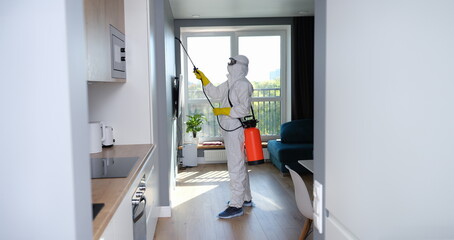 Man in protective suit treating with disinfectant flat. How to get rid of mold in apartments concept