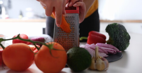 Chef grating carrots to make vegetable salad closeup. Vegetable recipes concept