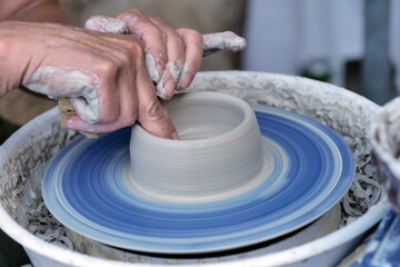 Female potter, ceramist working on pottery wheel while sitting in her workshop