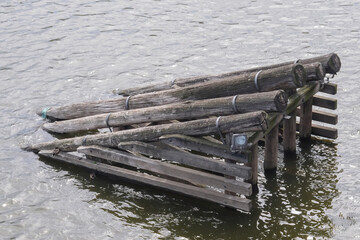 Old wooden breakwater. Construction of wooden trunks in the water.