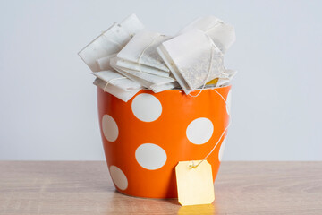 A pile of tea bags with a blank yellow label in a cup. Cozy template with space for text on the tag.