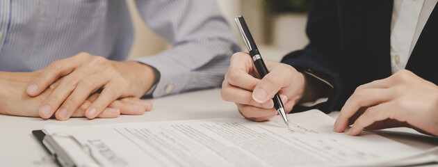 Close-up two business people holding pen and signing a contract trade document on the table.