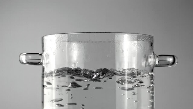 A monochromatic image of a glass cylinder filled with water, showcasing the beauty of tableware and the purity of liquid