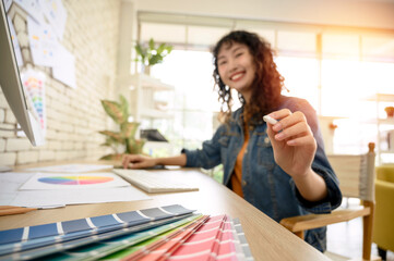 Happy blurred young woman graphic designer pointing finger at camera. Select focus to pen in hand.