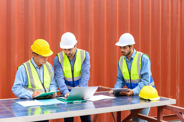 Group of container operators wearing helmets and safety vests meeting about logistics operations in container yards. Colleagues Talk About Logistics Operations