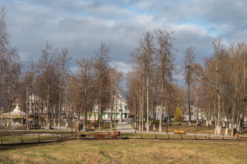 City park with alleys, walking paths and benches, a flowing river. Spring landscape.