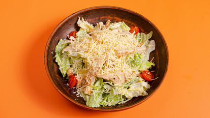 Caesar salad bowl isolated on orange background
