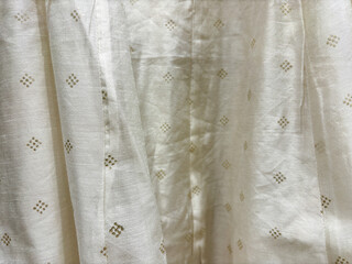 Closeup of a satin cream colour curtain with elegant dotted design.