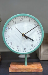 A green and white clock with the hands on the number 2 and 4, time showing 4:10.