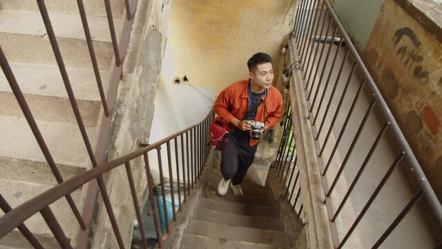 High angle shot of Asian man wandering through abandoned places to take photos for his blog