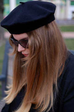 young blonde in a black beret and black glasses. woman in a beret and glasses, portrait photo of a blonde. Woman outdoors wearing sunglasses