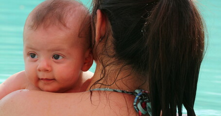 Mother holding baby at the swimming pool, kissing baby showing love and affection