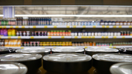 Close-up of many jam jars with metallic lids on a supermarket shelf