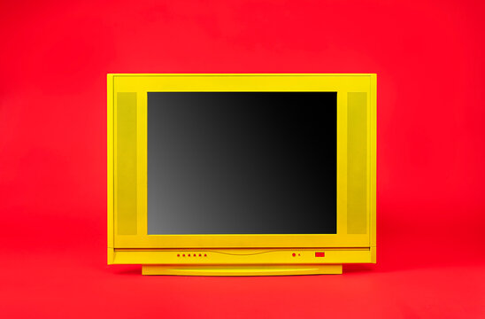 Yellow TV with black screen isolated on red background, front view