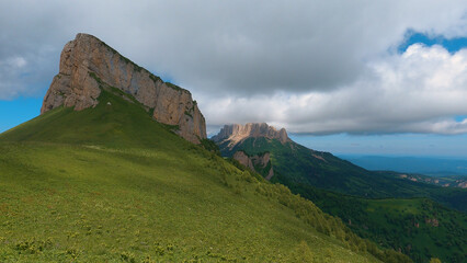 A spectacular view of the North Caucasus mountain range in southwestern Russia, showing the natural beauty of the rocky peaks under rain clouds.