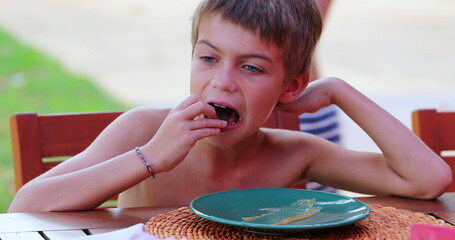 Young boy eating cookie outside