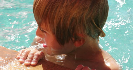 Young boy holding into swimming poolside
