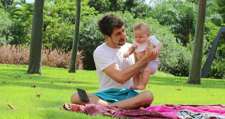Young Father holding baby toddler outside in nature at the park