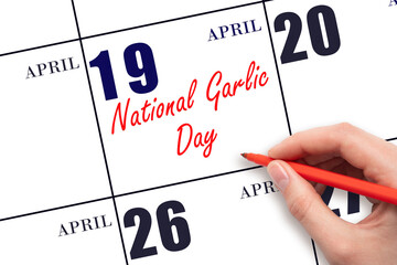 April 19. Hand writing text National Garlic Day on calendar date. Save the date.