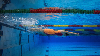 Female athlete swimming in the freestyle and making a flip turn to reverse direction in the pool, underwater wide.