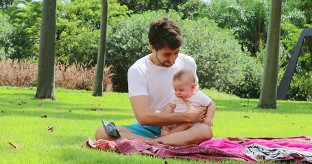 Young Father holding baby toddler outside in nature at the park