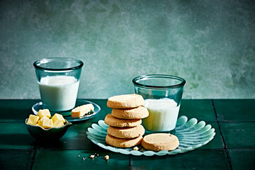All butter shortbread biscuits with butter cubes and glasses of milk