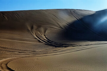 Hot deserts of southeastern part of the Arabian Peninsula. Eavening barchan dune (inland sandhill areas, drift sands) in January. Sand hills are used by Arab motorists as an autodrome (amateur rally) - obrazy, fototapety, plakaty