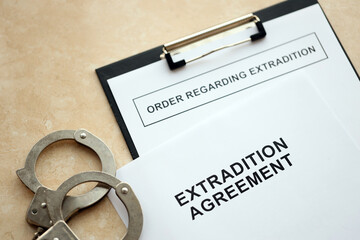 Extradition Agreement and Order Regarding Extradition with handcuffs on table close up
