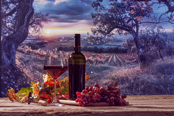 Wine bottle, glass with red wine, grape bunch, vine leaves on wooden table with beautiful nature...