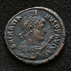 Ancient Roman coin of Emperor Gratian, top view of vintage metal money isolated on black background. Concept of old texture, Rome, portrait, Empire, antique and history - 779869789