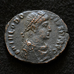 Ancient Roman coin of Emperor Theodosius I the Great, top view of vintage metal money isolated on black background. Concept of old copper texture, Rome, Byzantine Empire, antique