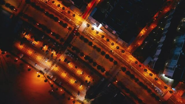 illuminated streets of Spanish touristic city Salou, Catalonia, aerial view of main street with alley of palm trees and lights, directly above 4k