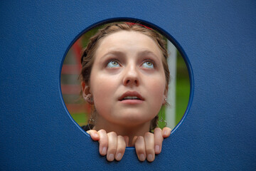 young woman looking up in kindergarten babysitter playing in game module hole blue plastic...