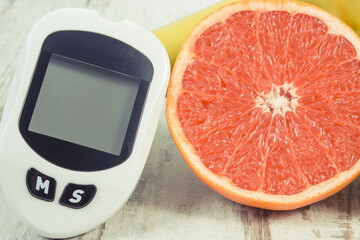 Glucometer for checking sugar level, ripe grapefruit and dumbbells for fitness. Healthy lifestyle and nutrition during diabetes