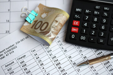 Obraz premium Many calculation results in schedules lies on table with canadian money bills, calculator and pen close up. Taxation and annual accountant paperwork in Canada
