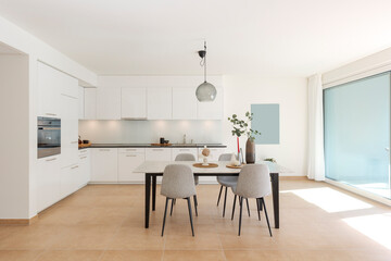 Large modern white kitchen with a marble table and four chairs in front. This is the interior of a modern flat. - 779879113