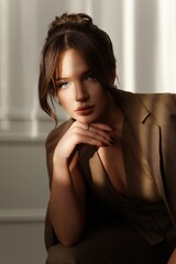 Portrait of a gentle girl in a brown suit. Brunette with blue eyes. Trendy studio shooting of the girl model.