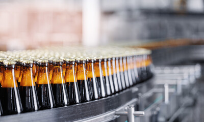 Automated modern beer bottling factory line with glasses bottles on conveyor. Banner Brewery industry food manufacturing, sunlight - obrazy, fototapety, plakaty